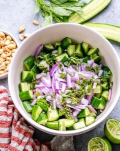 chopped cucumber in a bowl with red onion and basil