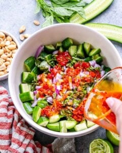pouring dressing over cucumbers