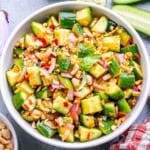 a round white bowl with cucumber salad with Thai dressing.