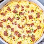 An egg baked with cottage cheese and turkey bacon in a dish over a tortilla.