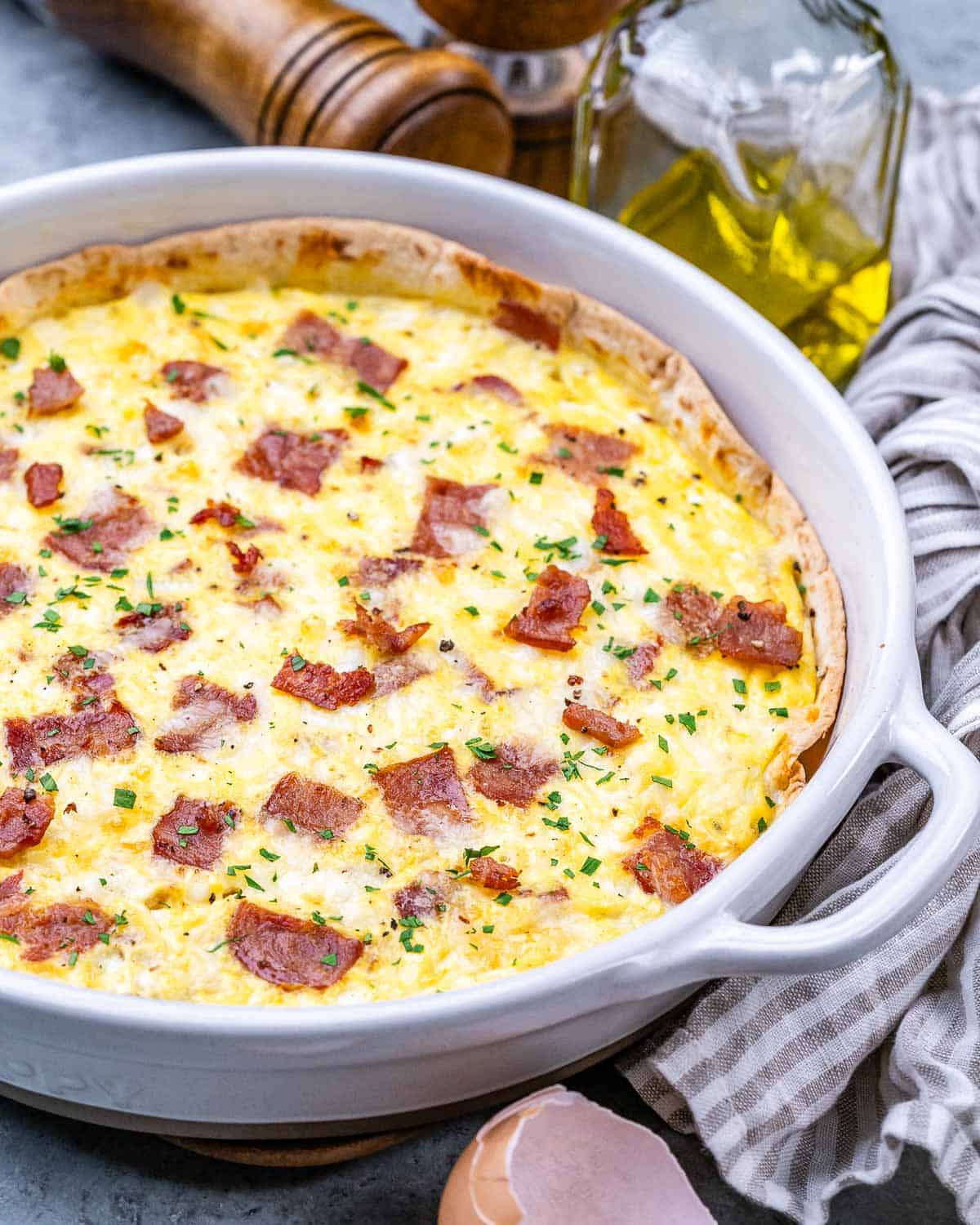 An egg baked with cottage cheese and turkey bacon in a dish over a tortilla.