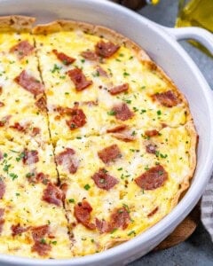 An egg baked with cottage cheese and turkey bacon in a dish over a tortilla.