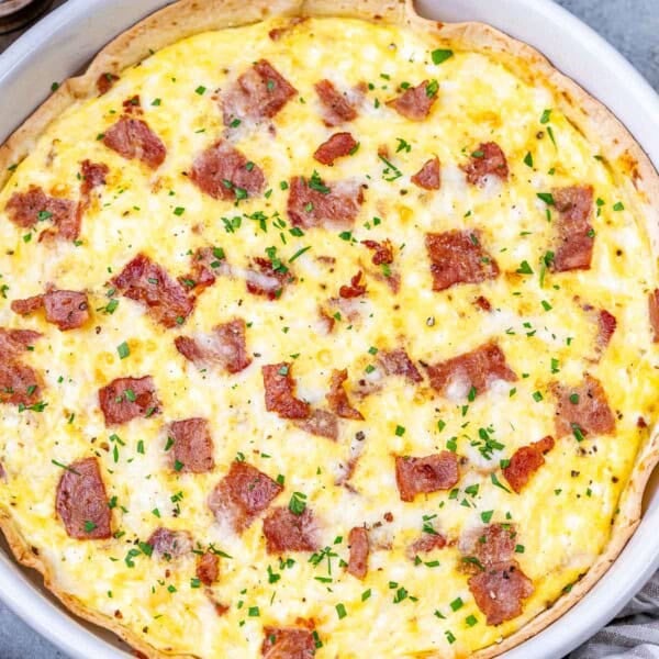 An egg baked with cottage cheese and turkey bacon in a dish over a tortilla.