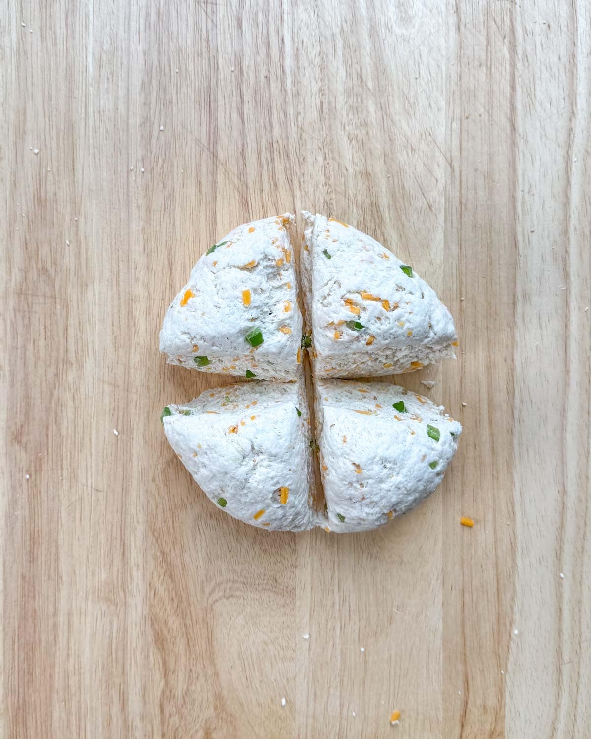 Zesty Jalapeno Cheddar Bagels 15 Bagel dough divided into 4 portions on a cutting board, ready for shaping.