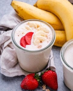 a jar with blended oats topped with sliced strawberries and bananas.