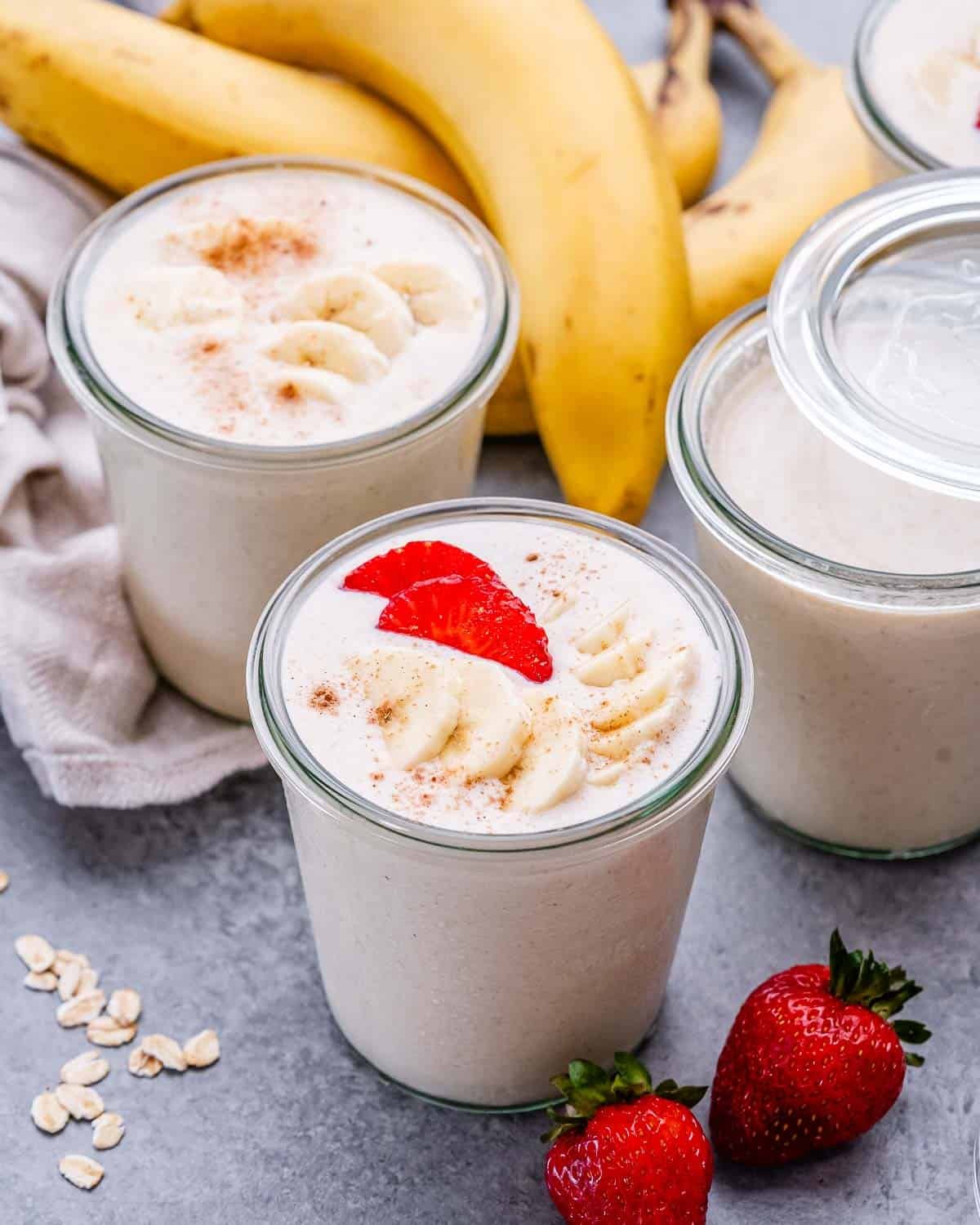 Jars of blended overnight oats with banana and strawberries on top