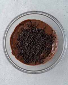 Mixing bowl filled with chocolate batter and dark chocolate chips just added on top.