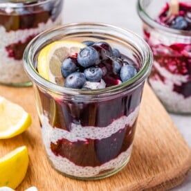 Close-up of a jar showing alternating layers of chia pudding and blueberry compote, topped with blueberries.