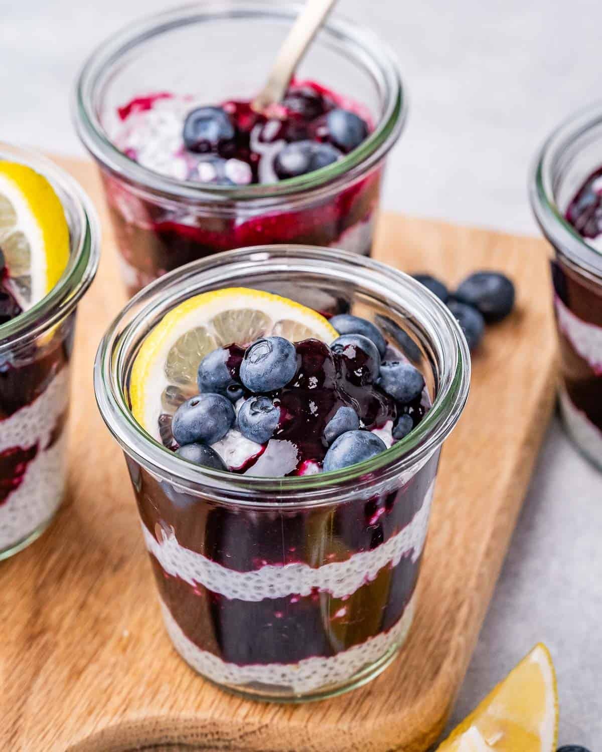 Close-up of a blueberry lemon chia pudding jar on a wooden board, showing the vibrant layers.