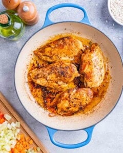Seasoned chicken breasts browning in a skillet before being added to the rice mixture.