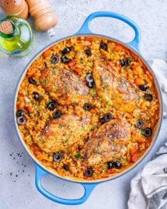 Skillet of cooked Spanish chicken and rice, topped with sliced black olives, ready to serve.