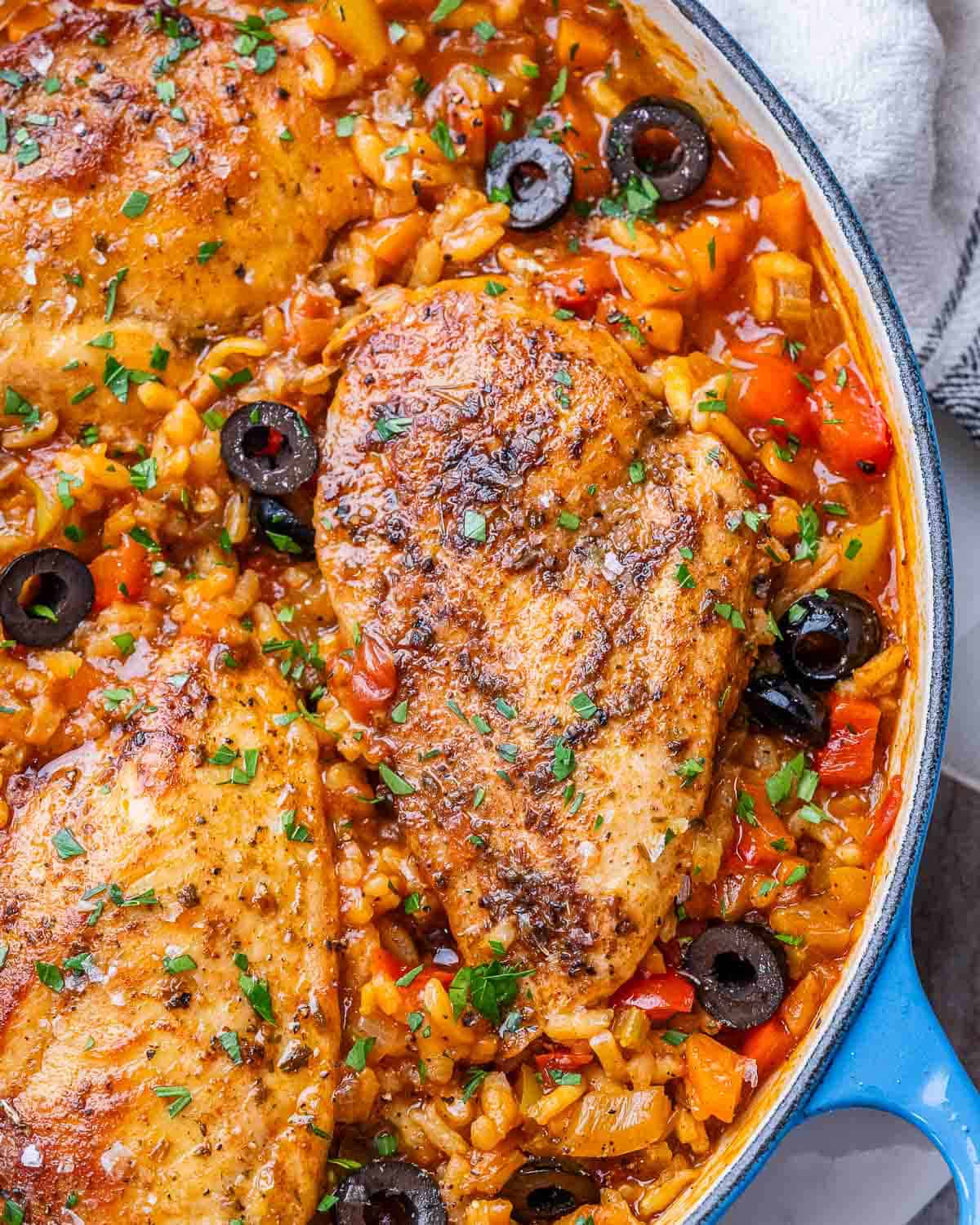 Overhead close-up of Spanish chicken and rice in a skillet, showing tender chicken and colorful peppers.