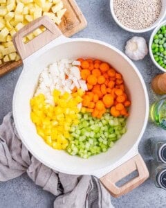 Chopped onion, celery, carrots, and yellow bell pepper in a pot, ready to be sautéed for the soup.