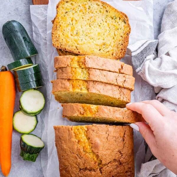 Hand grabbing a slice of zucchini and carrot bread.