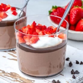 a cup with cottage cheese chocolate pudding, topped with yogurt and chopped strawberries.