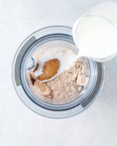 ingredients for chocolate pudding being added in a blender.