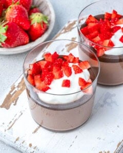 chocolate pudding in a cup topped with whipped cream and strawberries.