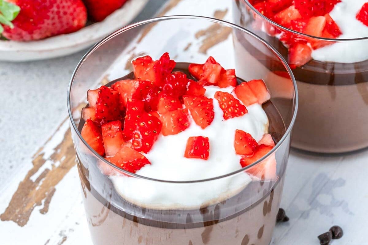 chocolate pudding in a cup topped with strawberries and whipped cream.