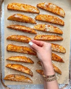Adding parmesan cheese over potato wedges.