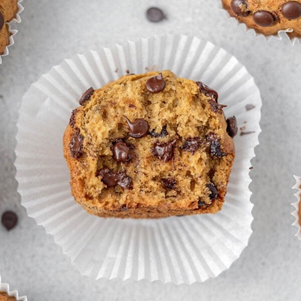 a single muffins cut in half over a muffin liner with melted chocolate chips in the middle.