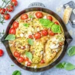 a skillet with chicken breast cooked in a creamy pesto sauce with tomatoes.