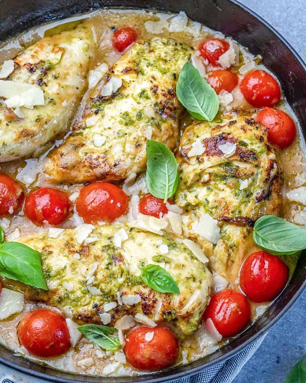 pesto baked chicken breast in a pan with creamy pesto sauce.