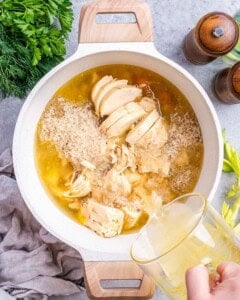 A pot filled with chicken, rice, and broth being prepared for the Avgolemono Soup base.