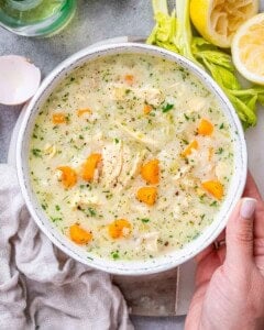 A pot of finished Avgolemono Soup with bright carrots, rice, and parsley, ready to be served
