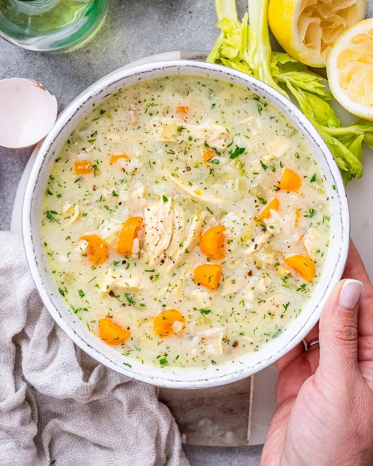 A pot of finished Avgolemono Soup with bright carrots, rice, and parsley, ready to be served