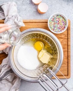 Butter, coconut oil, sugar, egg, and vanilla being whipped together in a mixing bowl.