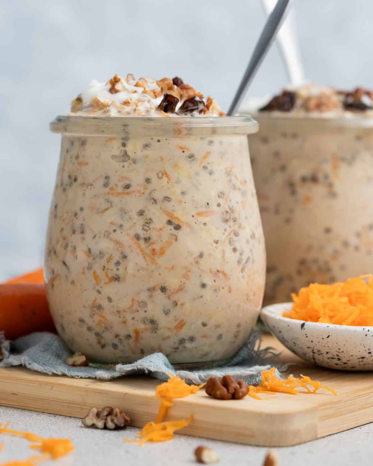 Two jars of carrot cake overnight oats on a wooden board.