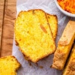Two slices of carrot cake loaf on parchment paper, with soft crumbs and visible raisins.