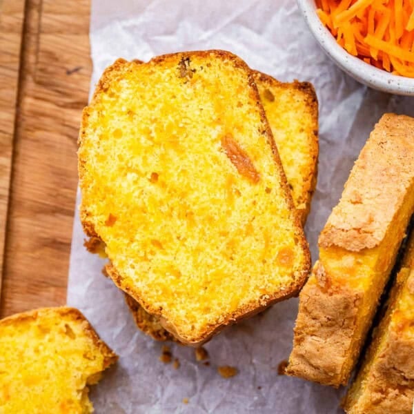 Two slices of carrot cake loaf on parchment paper, with soft crumbs and visible raisins.