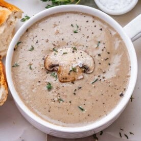 mushroom soup in a round white bowl with a slice of mushroom as garnish.