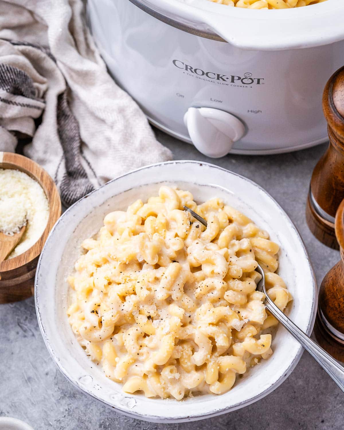 mac and cheese in a white bowl next to a crockpot