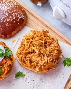 Overhead view of shredded BBQ chicken piled high on an open sandwich bun.