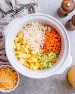 The full crockpot filled with potatoes, chopped carrots, celery, onion.