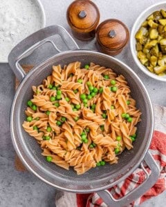 Cooked lentil rotini pasta in a colander, drained and sprinkled with fresh chopped dill.