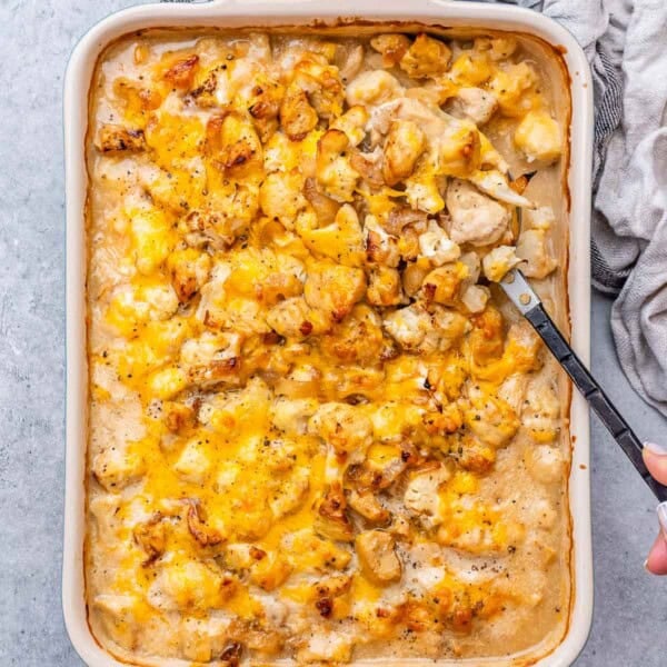 a dish with chicken and cauliflower topped with cheese.
