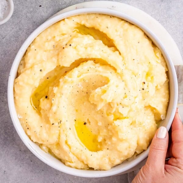 Creamy mashed potatoes served in a white bowl with melted butter swirled on top.