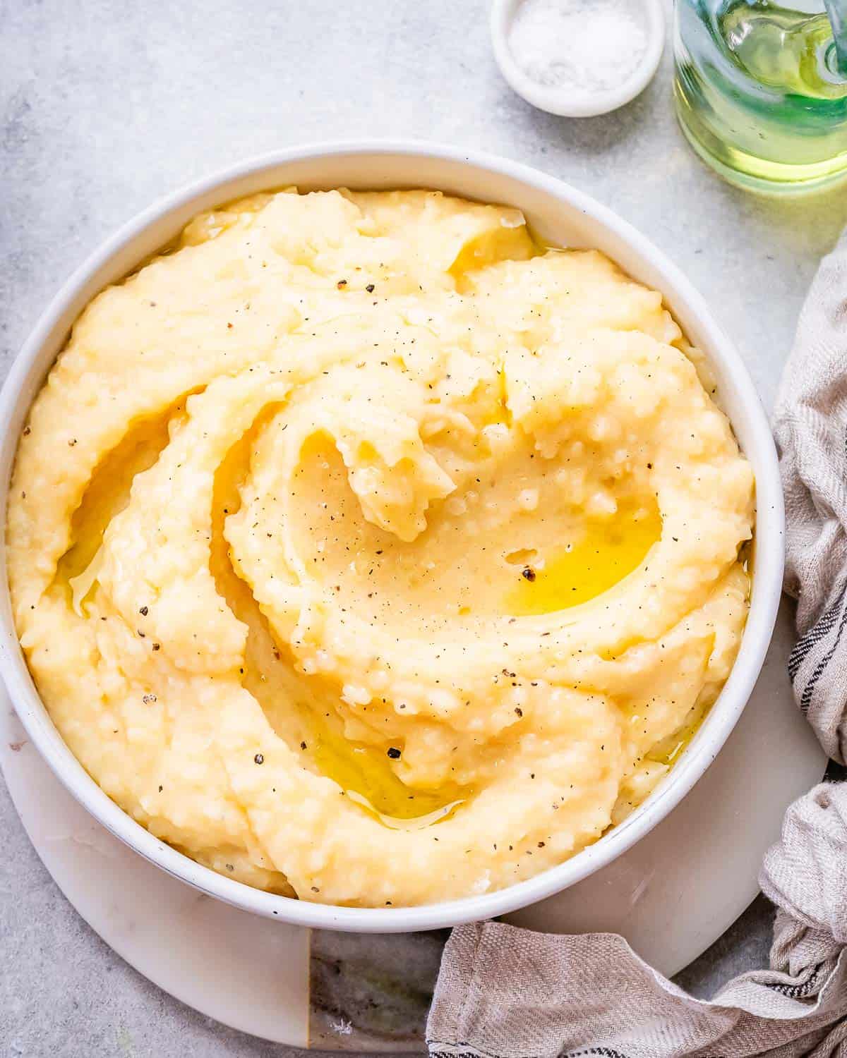 Smooth golden mashed potatoes in a serving bowl with swirls of melted butter.