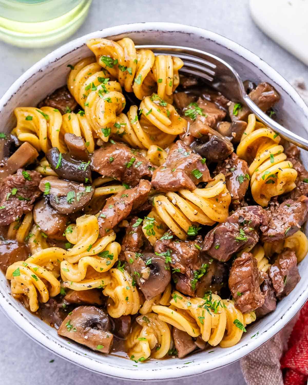 Top view of cooked beef stroganoff with tender beef, mushrooms, and pasta coated in a creamy sauce.