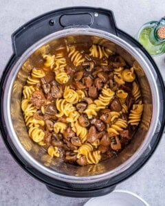Overhead shot of beef stroganoff served inside the Instant Pot with golden pasta and mushrooms.