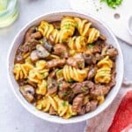 Freshly cooked stroganoff in a white bowl with rotini pasta, beef, and mushrooms mixed together.
