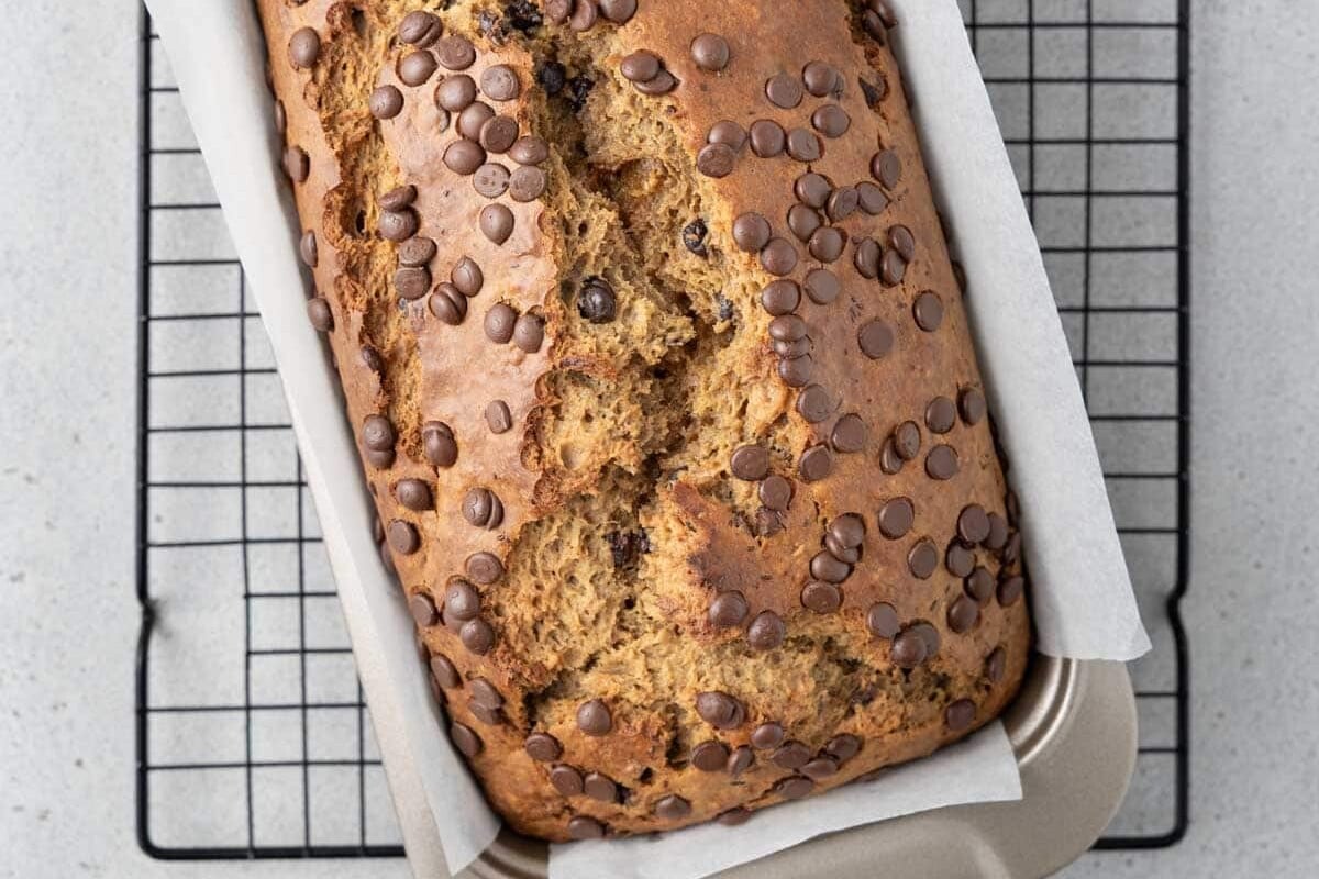banana bread in a pan on a wire rack.