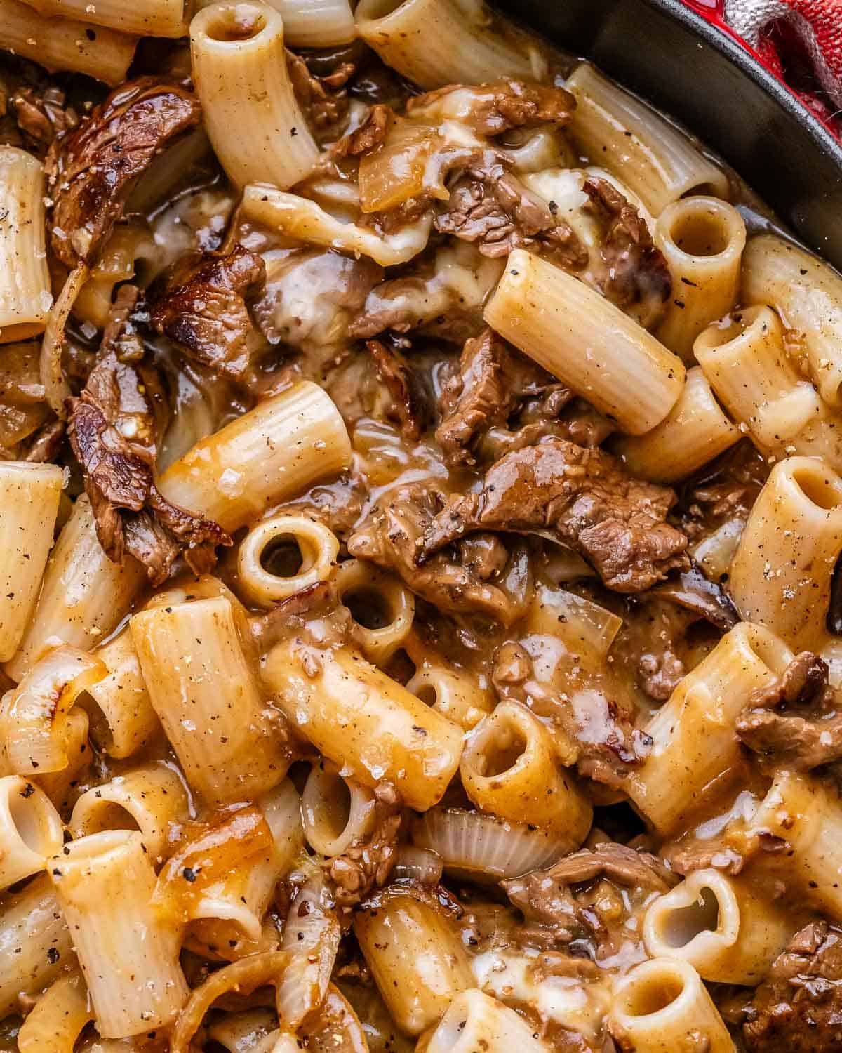 A closeup of Philly cheesesteak pasta in a cast iron skillet