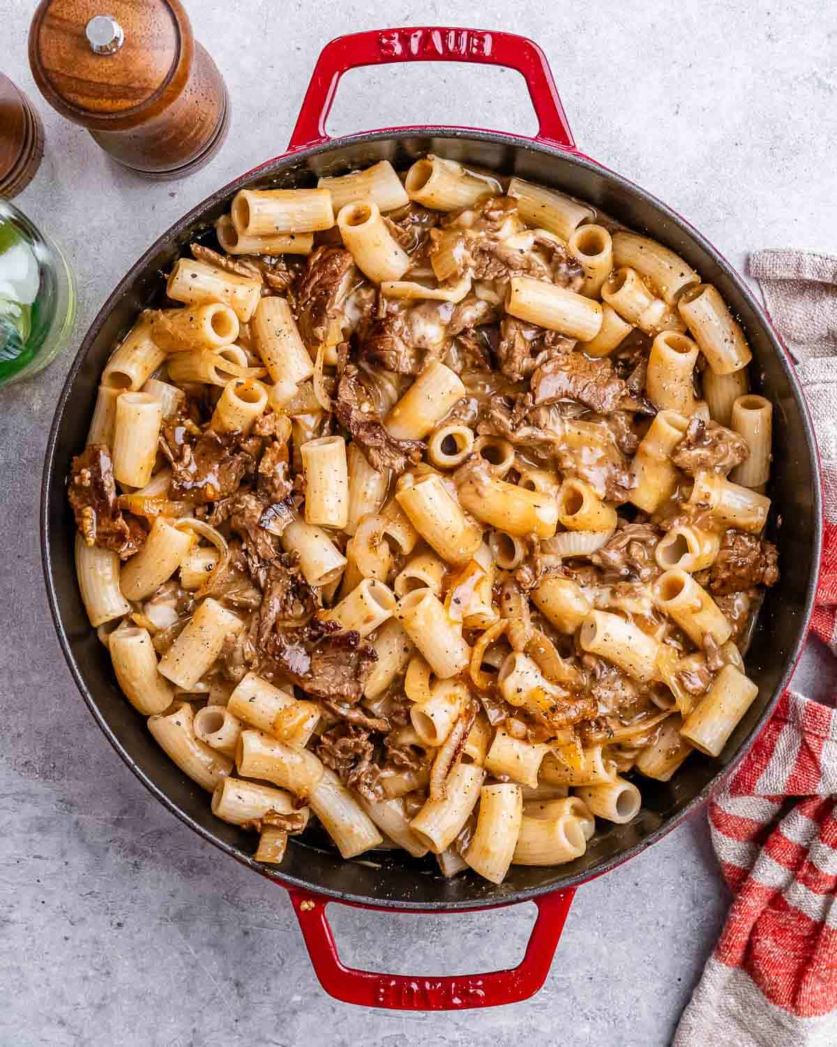 a red skillet with cheesy pasta and steak bites.