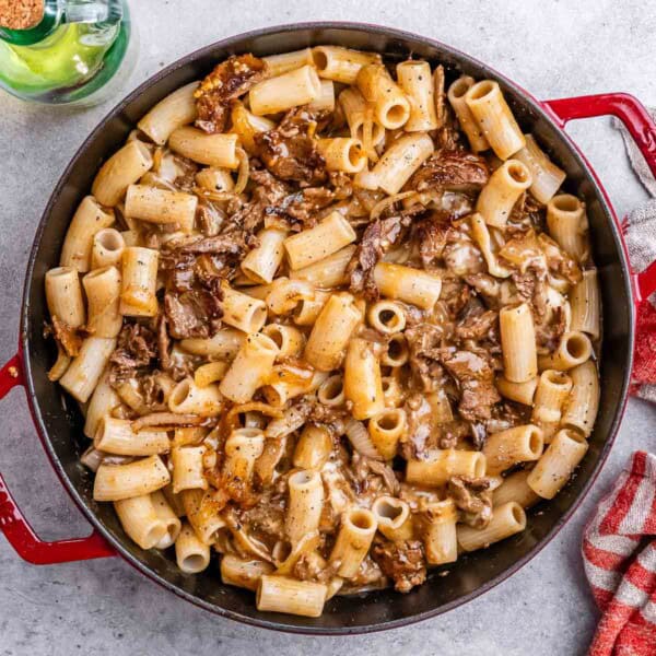 pasta with steak bites in a red skillet.