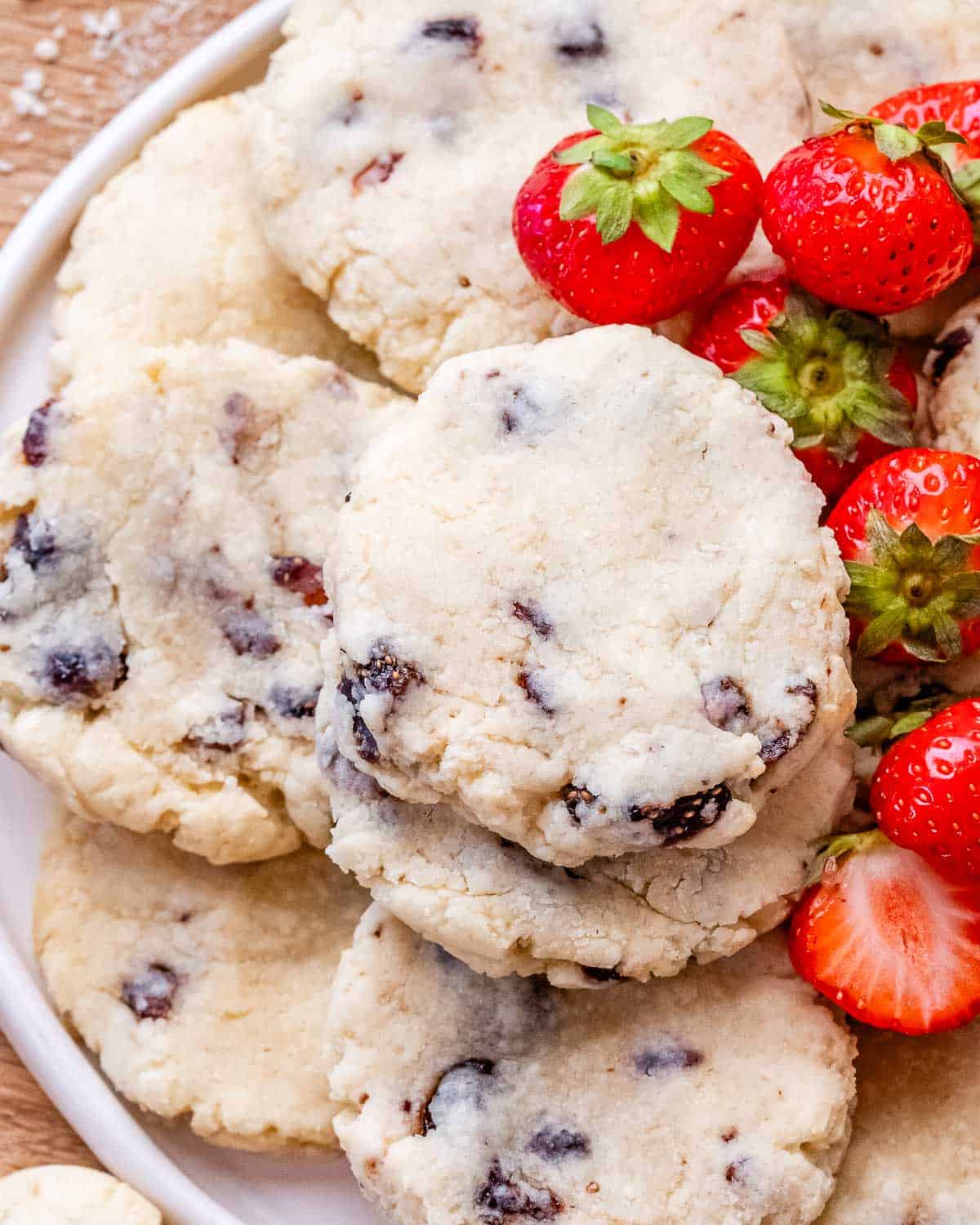 Close-up of a cookie stack showing the chewy texture and strawberry pieces inside, with whole fresh strawberries on the side.