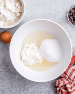 Cream cheese, sugar, and oil in a white mixing bowl at the start of the batter prep.